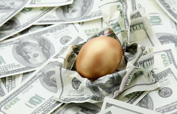 A golden egg resting on a pile of dollar bills
